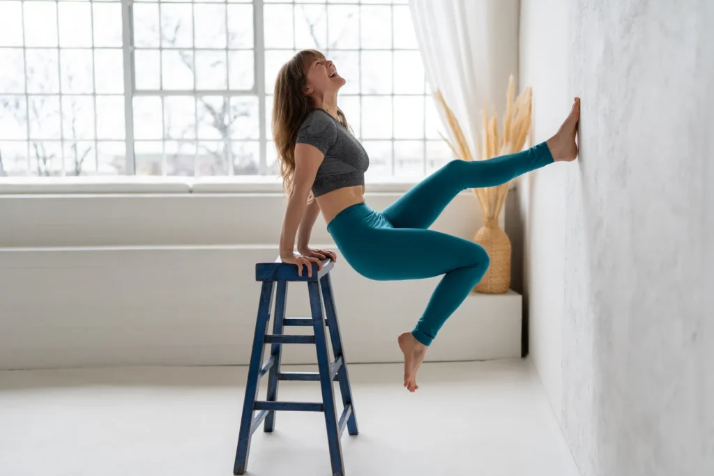 Žena v jógovém oblečení na barové stoličce s úsměvem a radostí po praxi dynamické jógy.