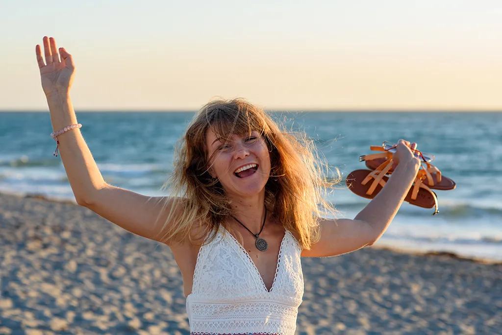 Žena radostně roztahuje náruč a zvedá paže po praxi jógy.